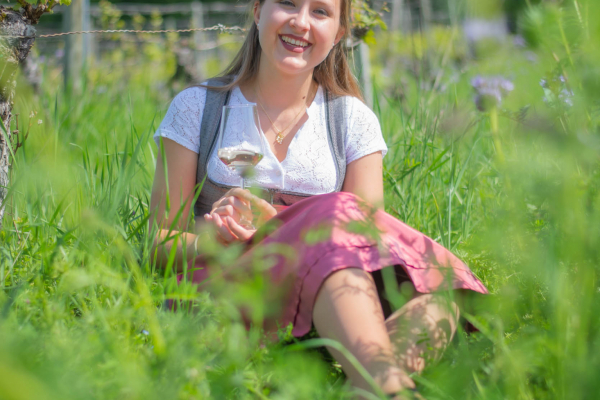 Weinprinzessin in den Weinbergen sitzend und lächelnd