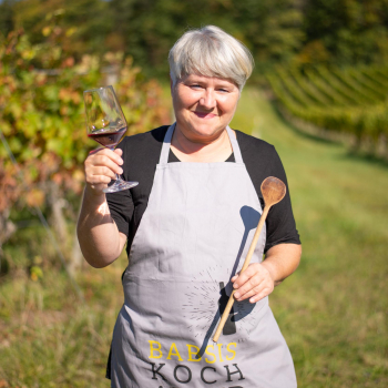 Frau mit Babsis Kochabend Schürze im Weinberg stehend