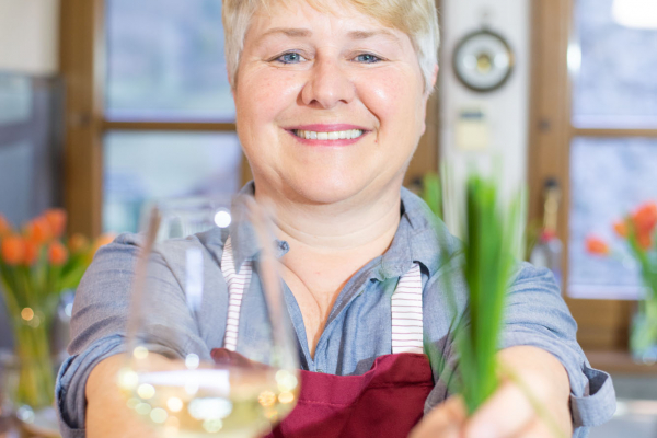 Frau lachend und Weinglas und Schnittlauch von sich streckend