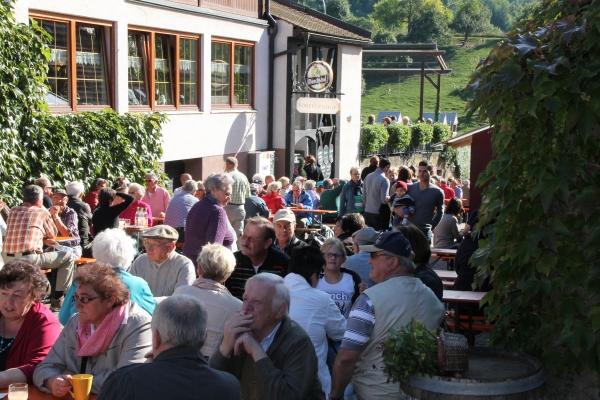 Viele Menschengruppen an Bierbänken in einem Hof sitzend