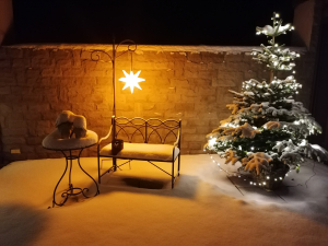 EIne Bank und ein kleiner weihnachtsbaum im Schnee beleuchtet